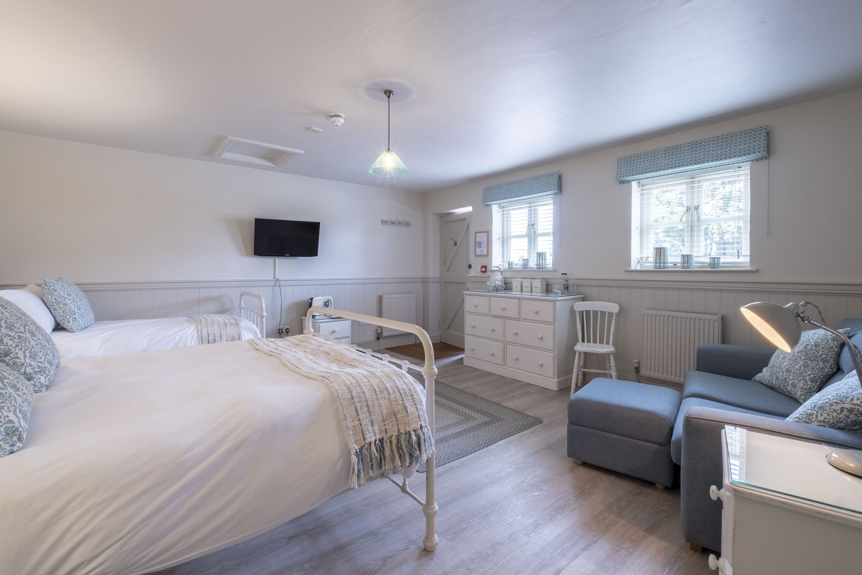 Un dormitorio con cama, mesita de noche, cómoda y escritorio con lámpara.