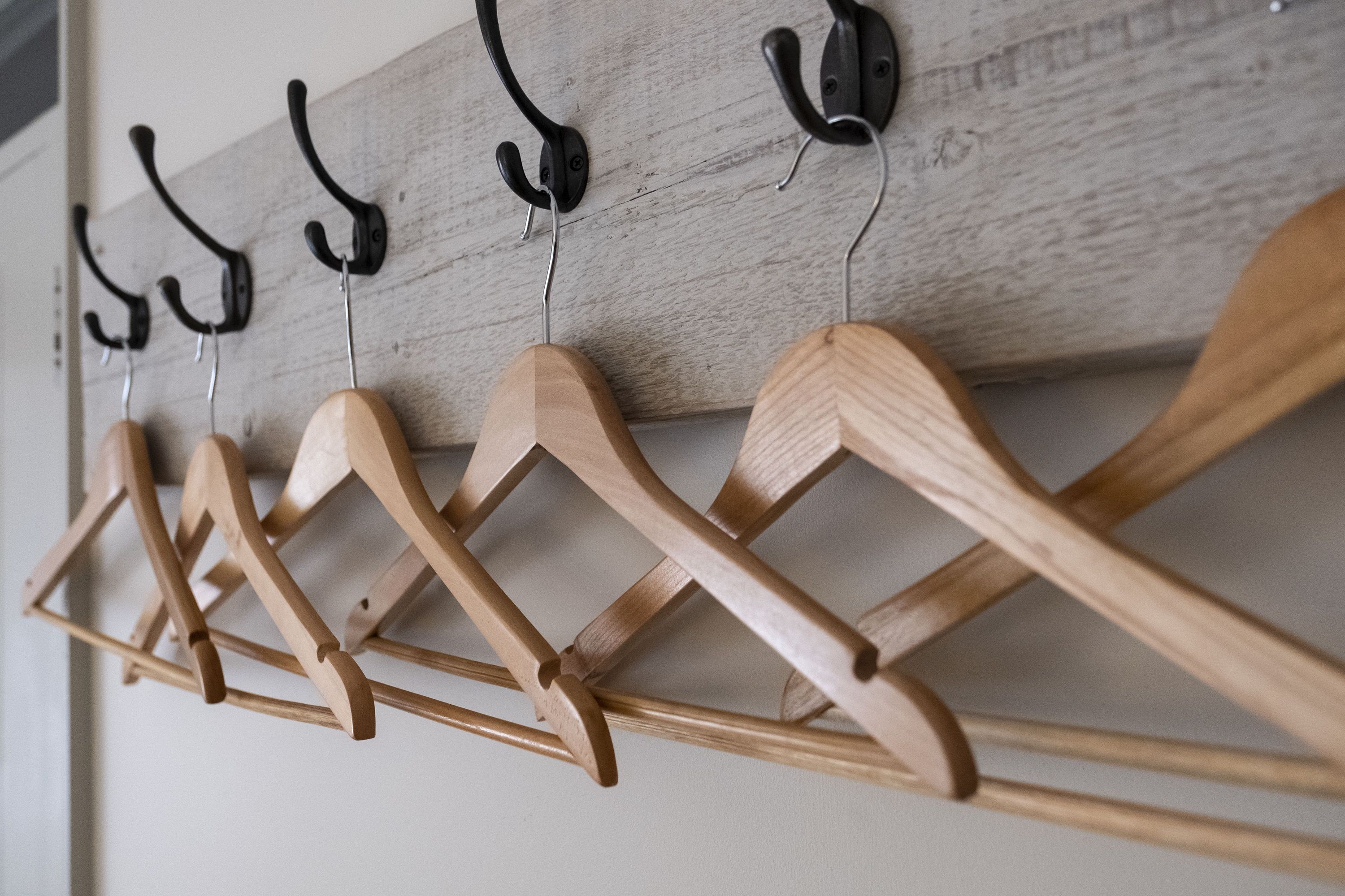 Un porte-manteau en bois, doté de plusieurs crochets, est fixé à un mur de couleur claire.