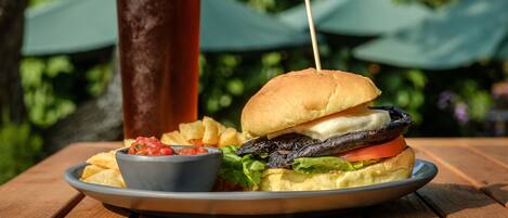 Un plato con una hamburguesa, papas fritas y una bebida sobre una mesa de madera.