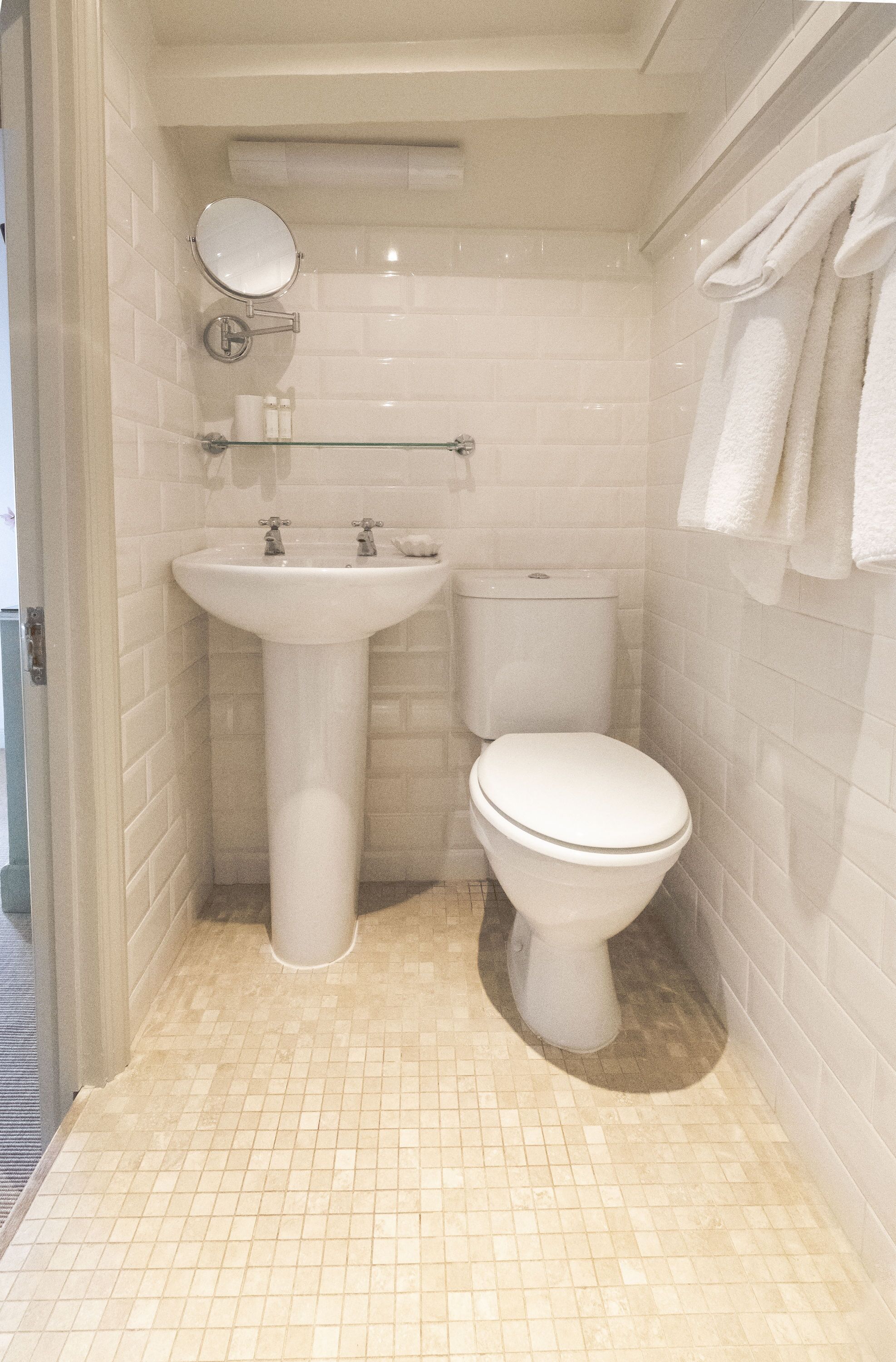 Un baño pequeño y limpio con lavamanos, inodoro y espejo blancos.