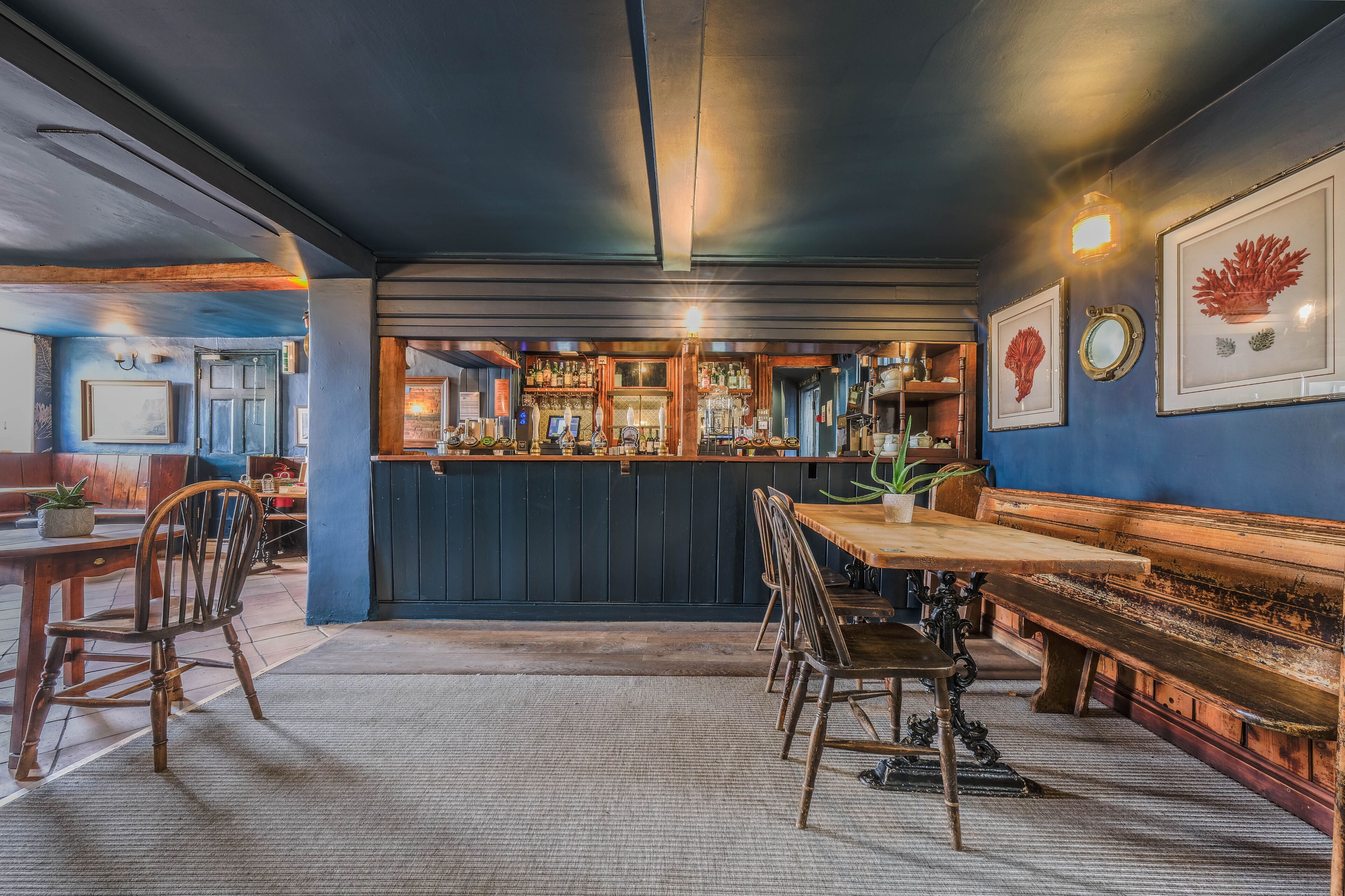 Una zona de bar con mobiliario de madera, una barra con botellas y obras de arte enmarcadas en la pared.
