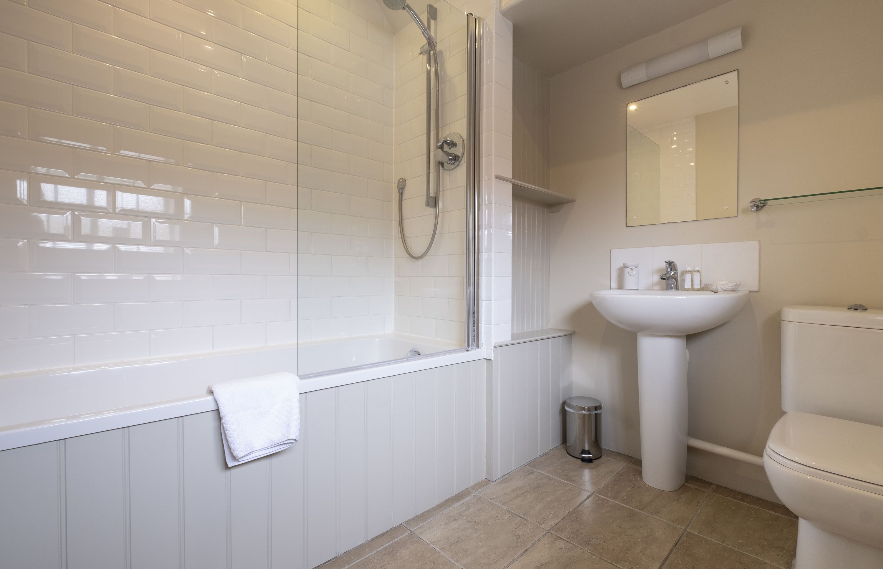 A modern bathroom with a white bathtub, a shower, a sink, and a toilet.