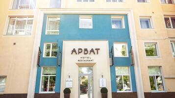 Welcome to APBAT Hotel and Restaurant, featuring a modern facade with a glass door entrance and potted plants.