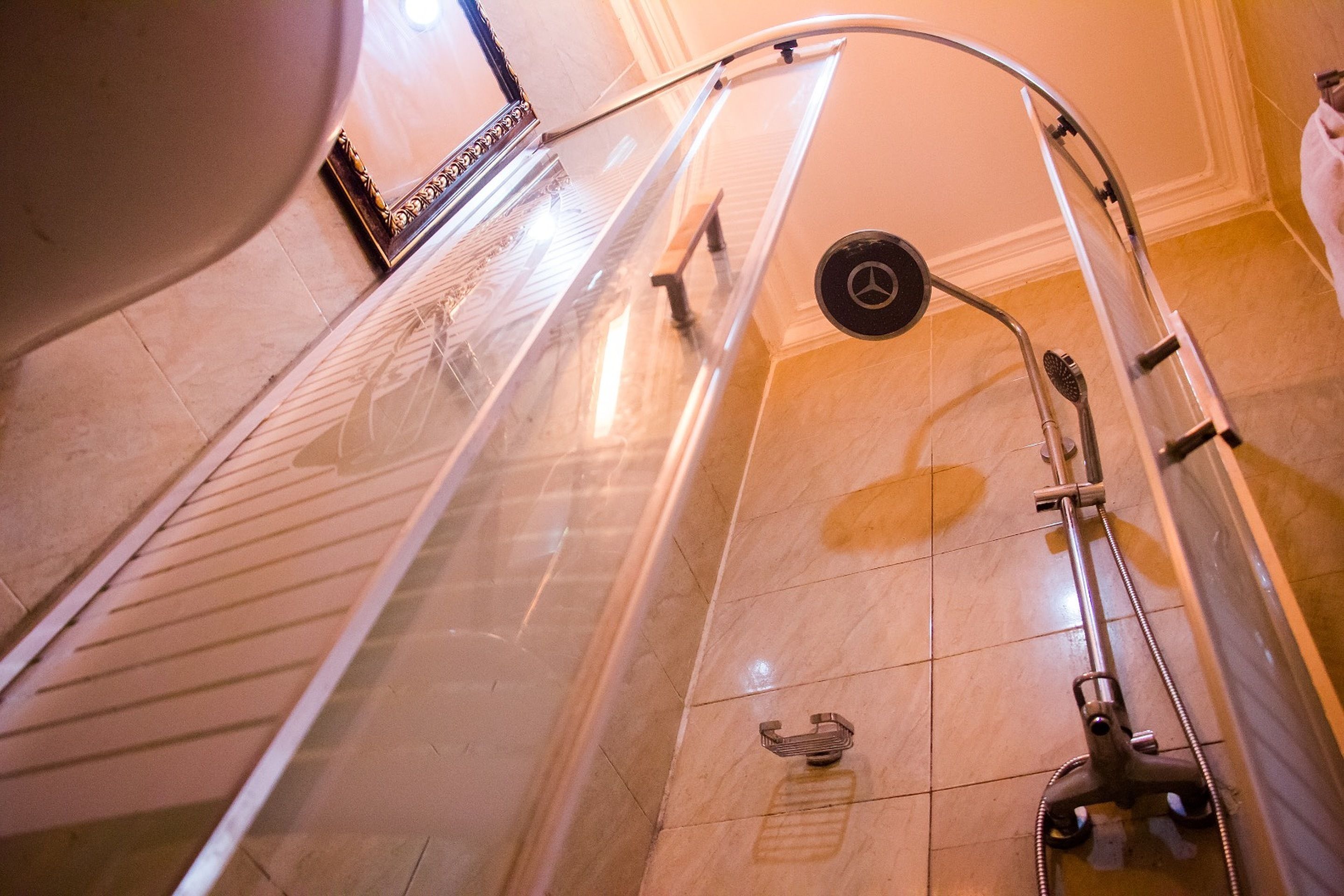 A shower with a glass door, a handheld showerhead, and a floor-mounted control panel.
