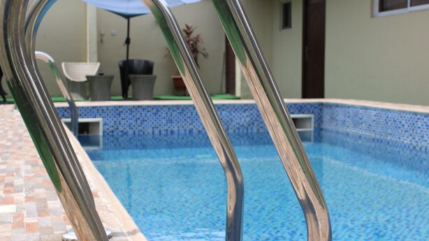 Una piscina con borde de azulejos y escalera metálica.