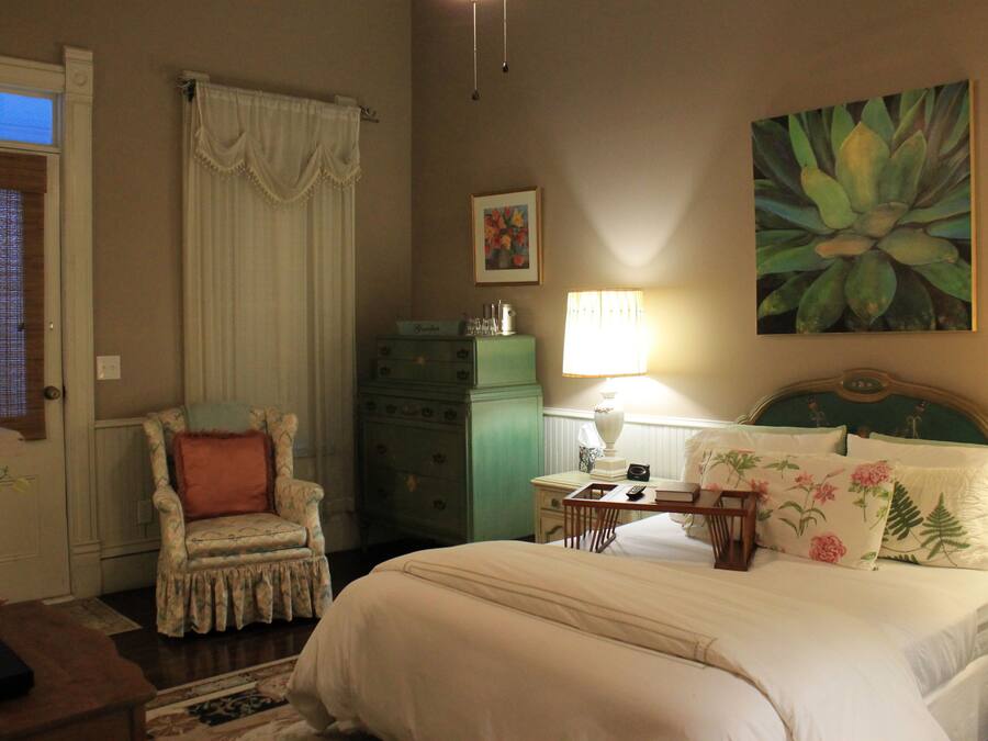 A bedroom with a bed, a chair, a dresser, a lamp, and a painting on the wall.