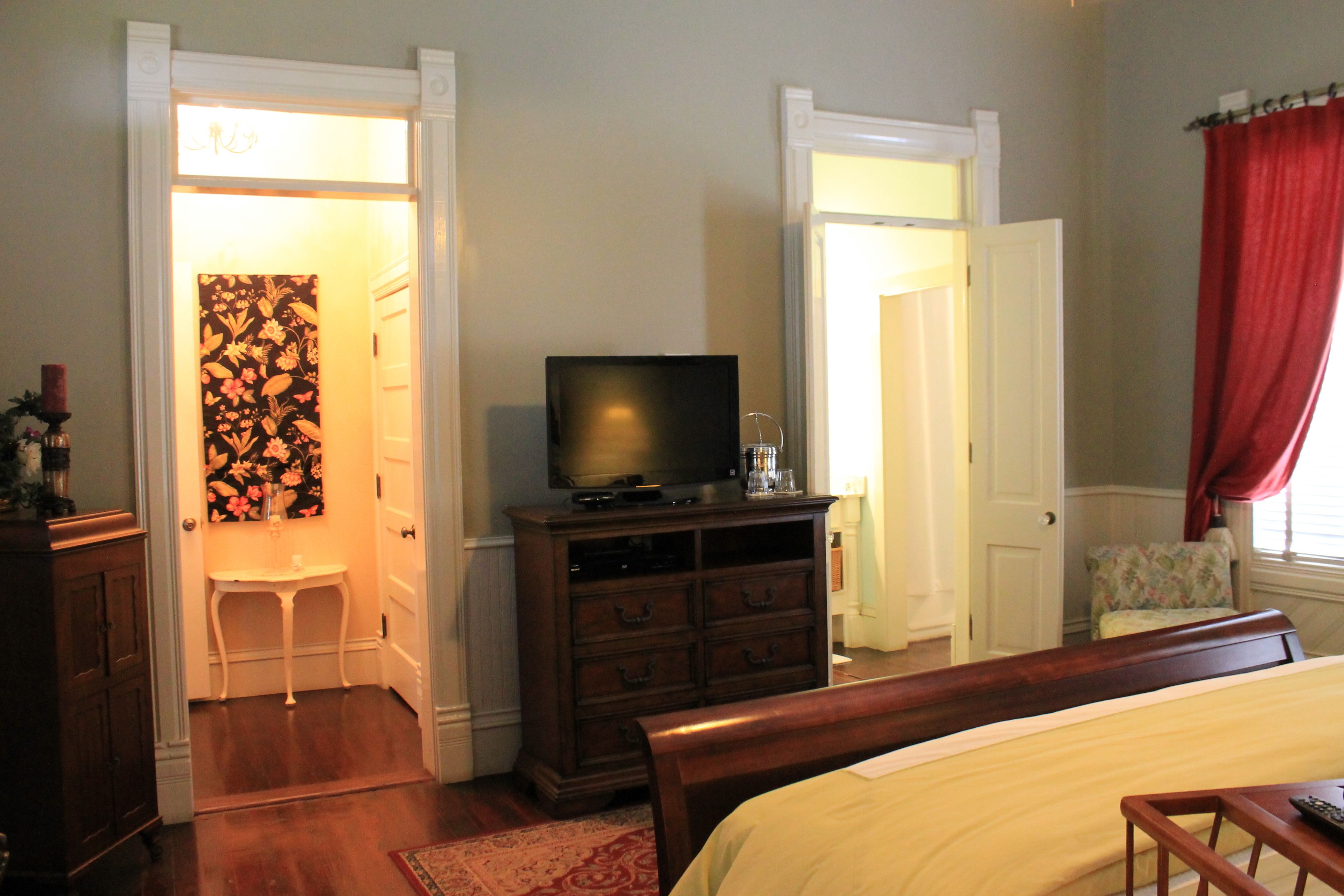 Un dormitorio con cama, cómoda, televisor y una silla.