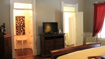 Un dormitorio con cama, cómoda, televisor y una silla.