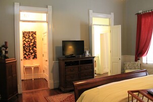 Un dormitorio con cama, cómoda, televisor y una silla.