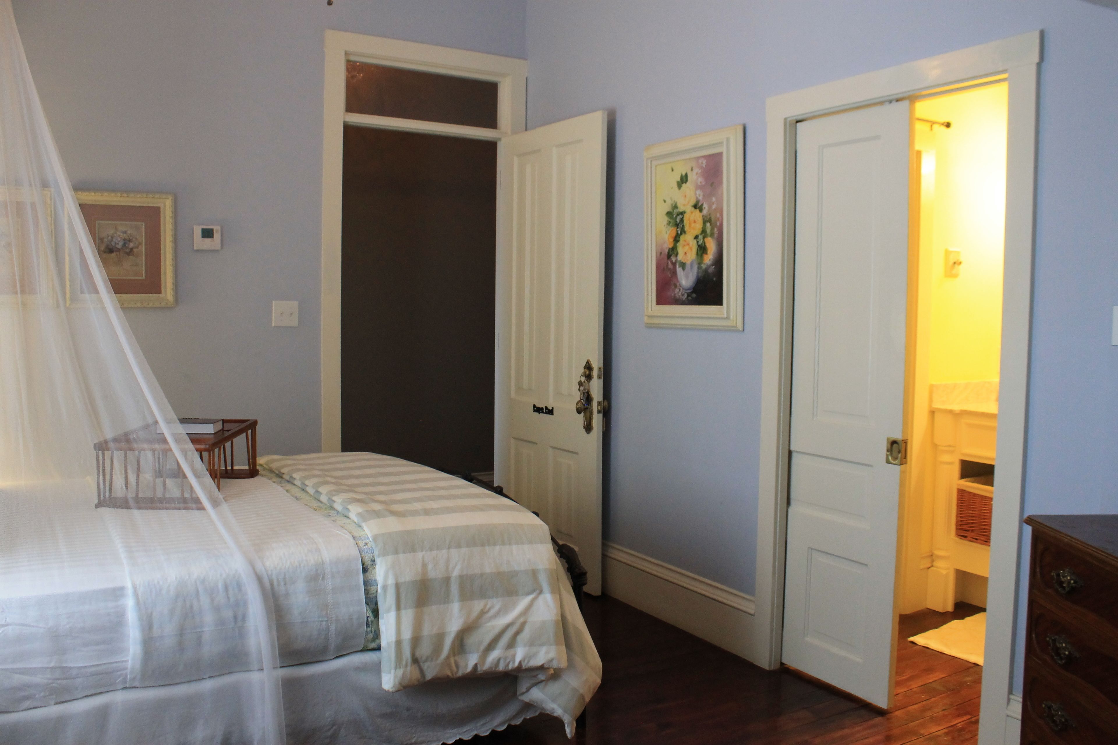 A bedroom with a bed, a door, a dresser, and a nightstand.