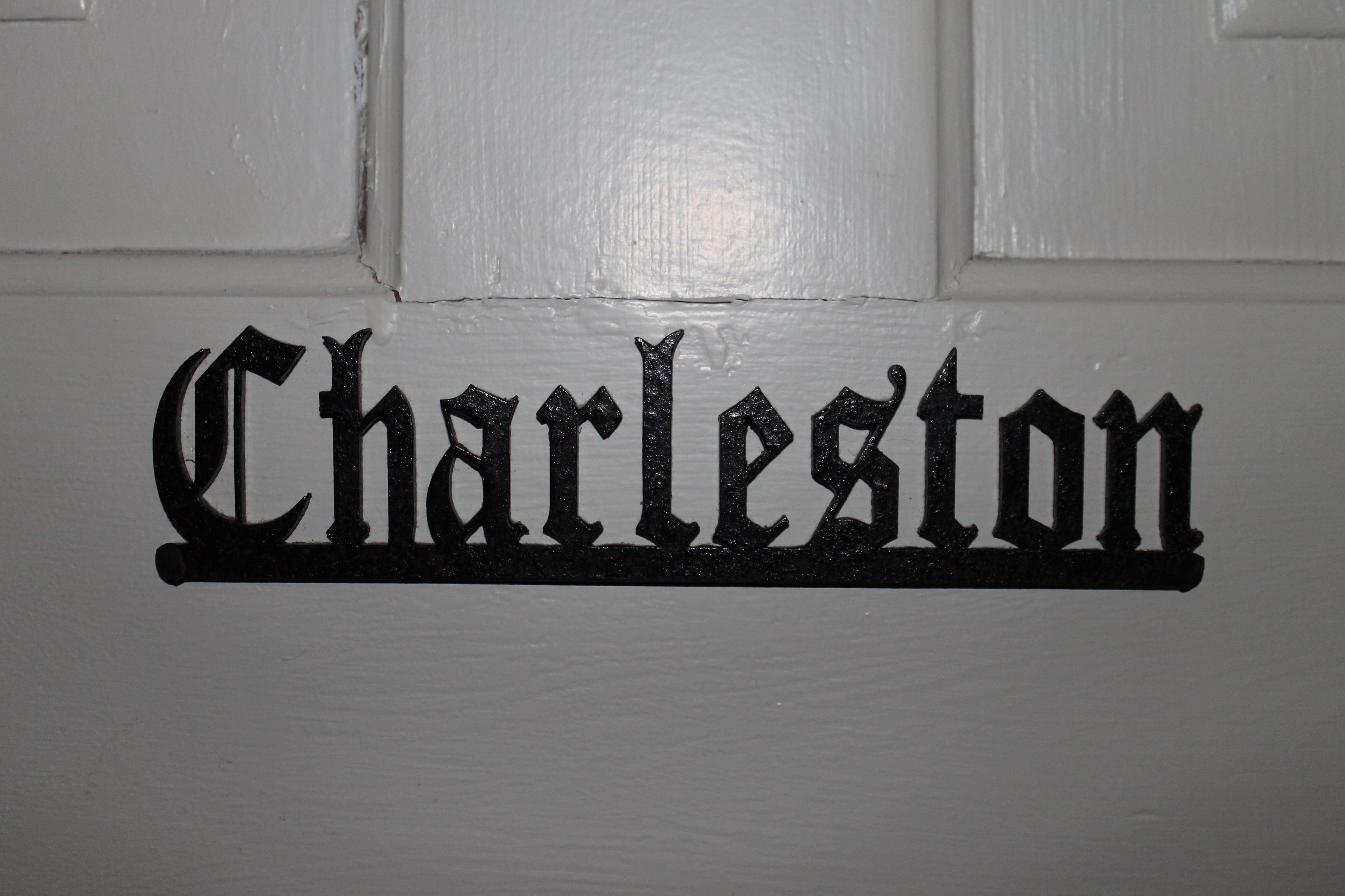 Eine weiße Tür mit dem Wort "Charleston" in schwarzer, gotischer Schrift.