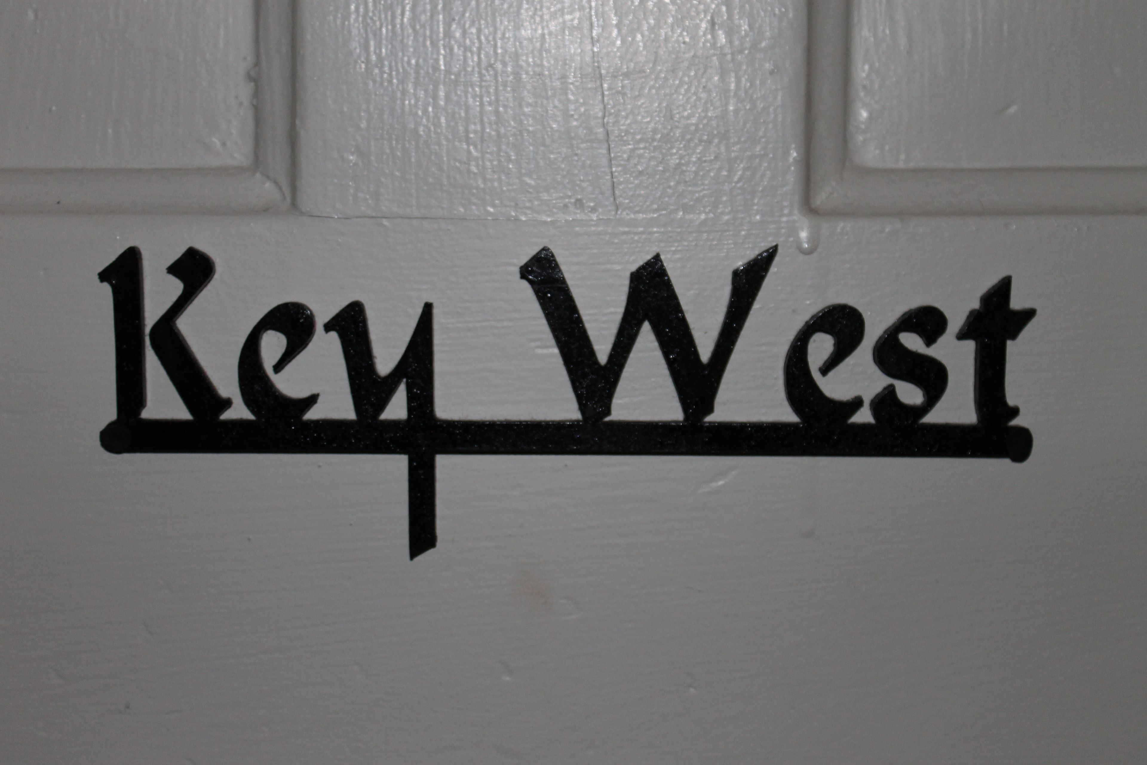 A sign with the text "Key West" on a white background.