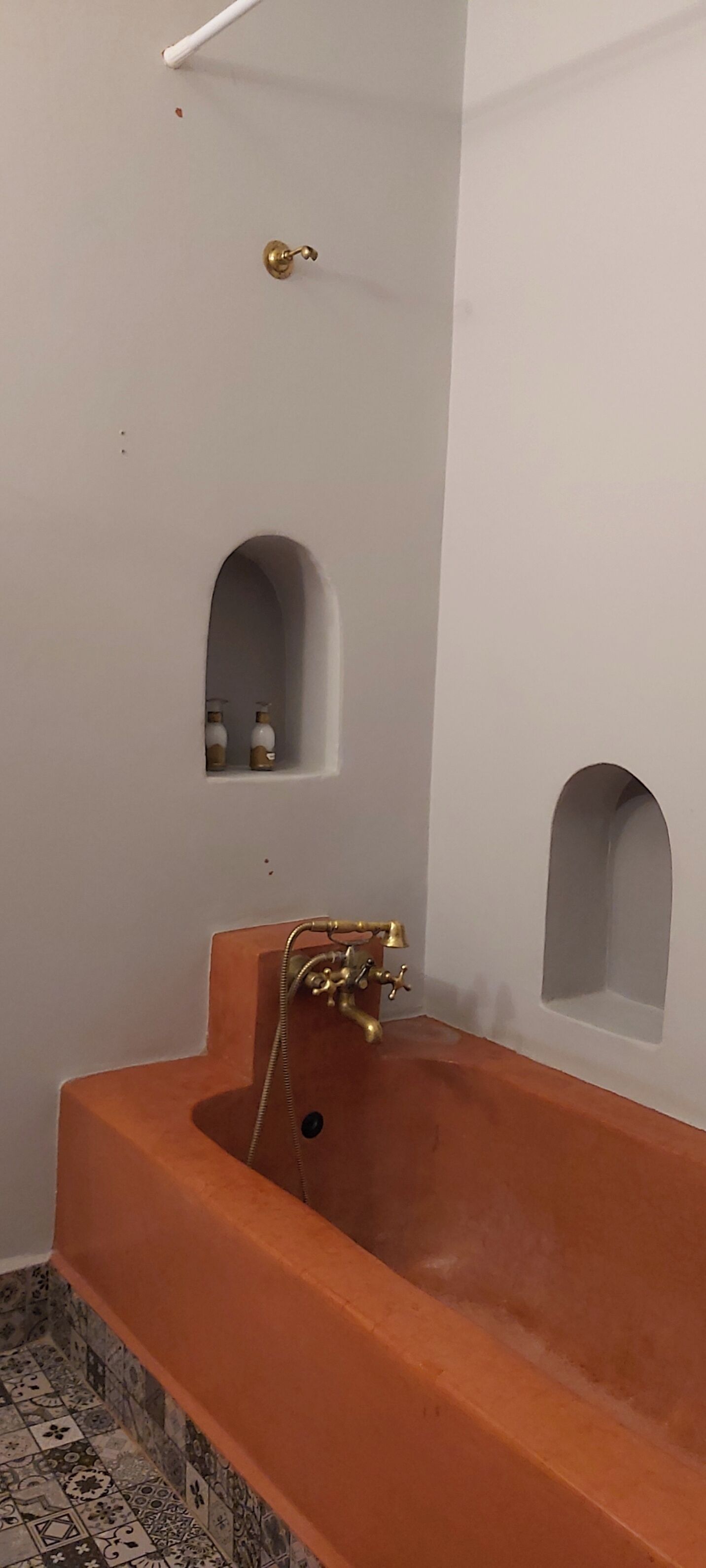 A bathroom with a large bathtub, a shower, and two small shelves with bottles.
