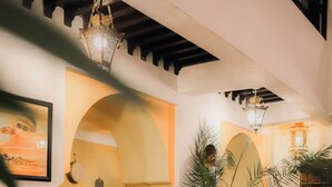 A dining area with a table set for four, surrounded by chairs, in a room with arches and a tiled floor. - Riad Ajebel (Marrakech)