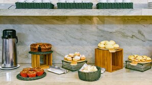 A buffet with various baked goods, including pastries and muffins, arranged on a marble countertop. - Plaza Inn Breeze Aeroporto (Goiania)
