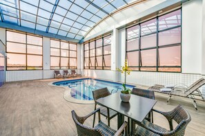 A spacious indoor pool area with a glass ceiling, a pool table, and wicker chairs. - Plaza Inn Breeze Aeroporto (Goiania)