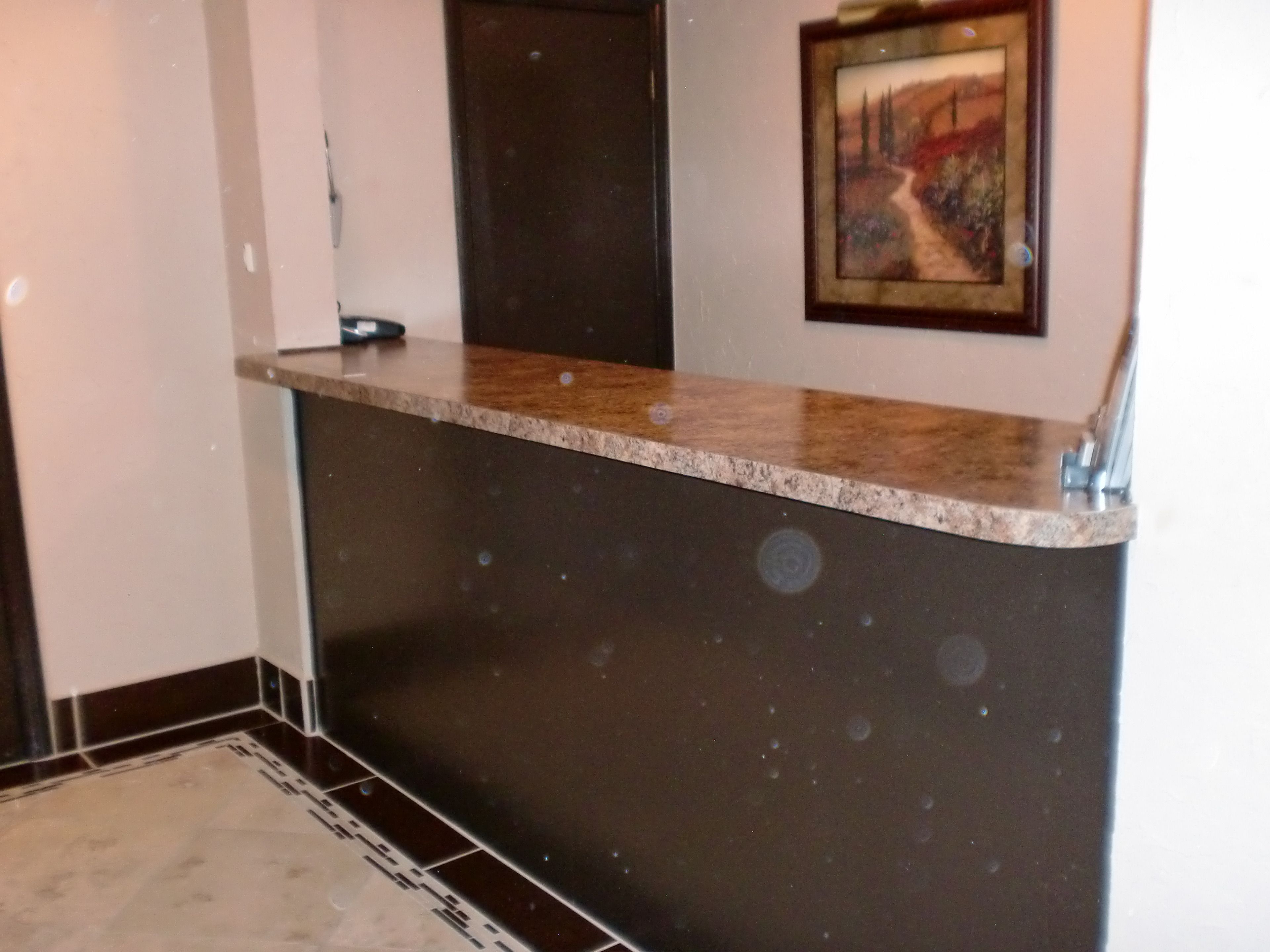 A reception desk with a marble top and a dark wall below.