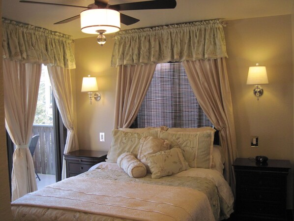 A bedroom with a bed, two bedside lamps, a ceiling fan, and a window with blinds.
