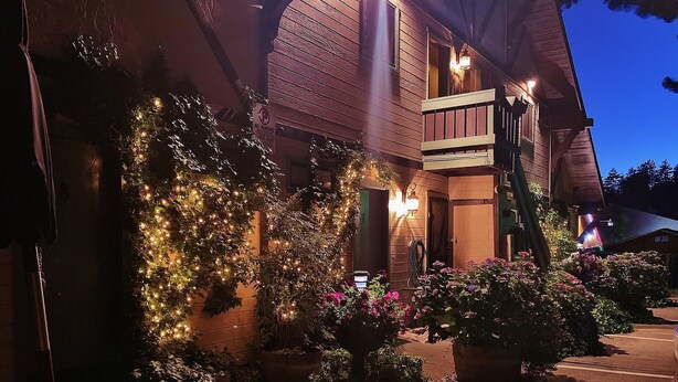 Un edificio in legno con un balcone, un cartello con la scritta 'No Parking' e luci decorative su una vite.