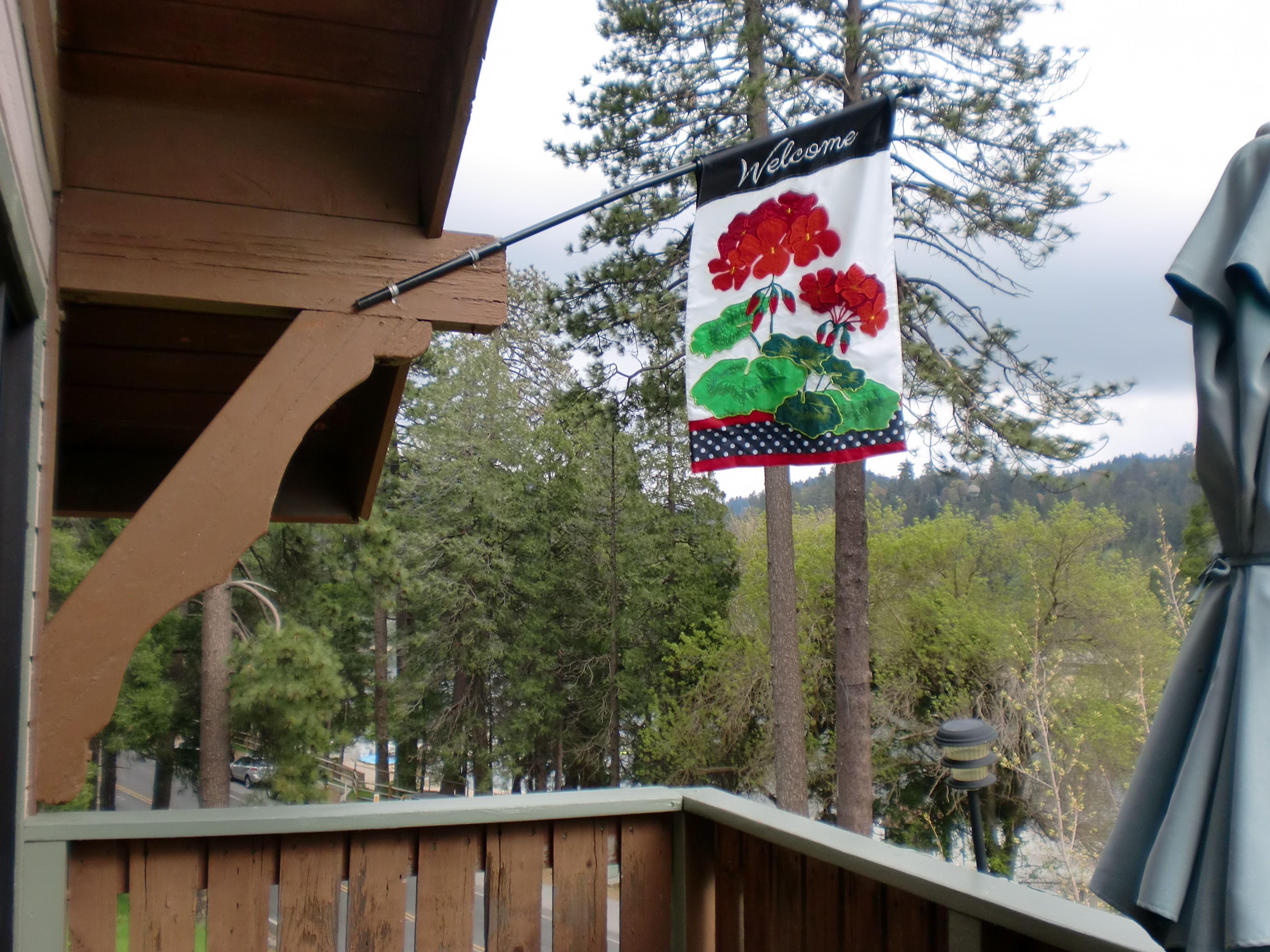 A wooden deck with a 'Welcome' sign featuring red flowers and green leaves.