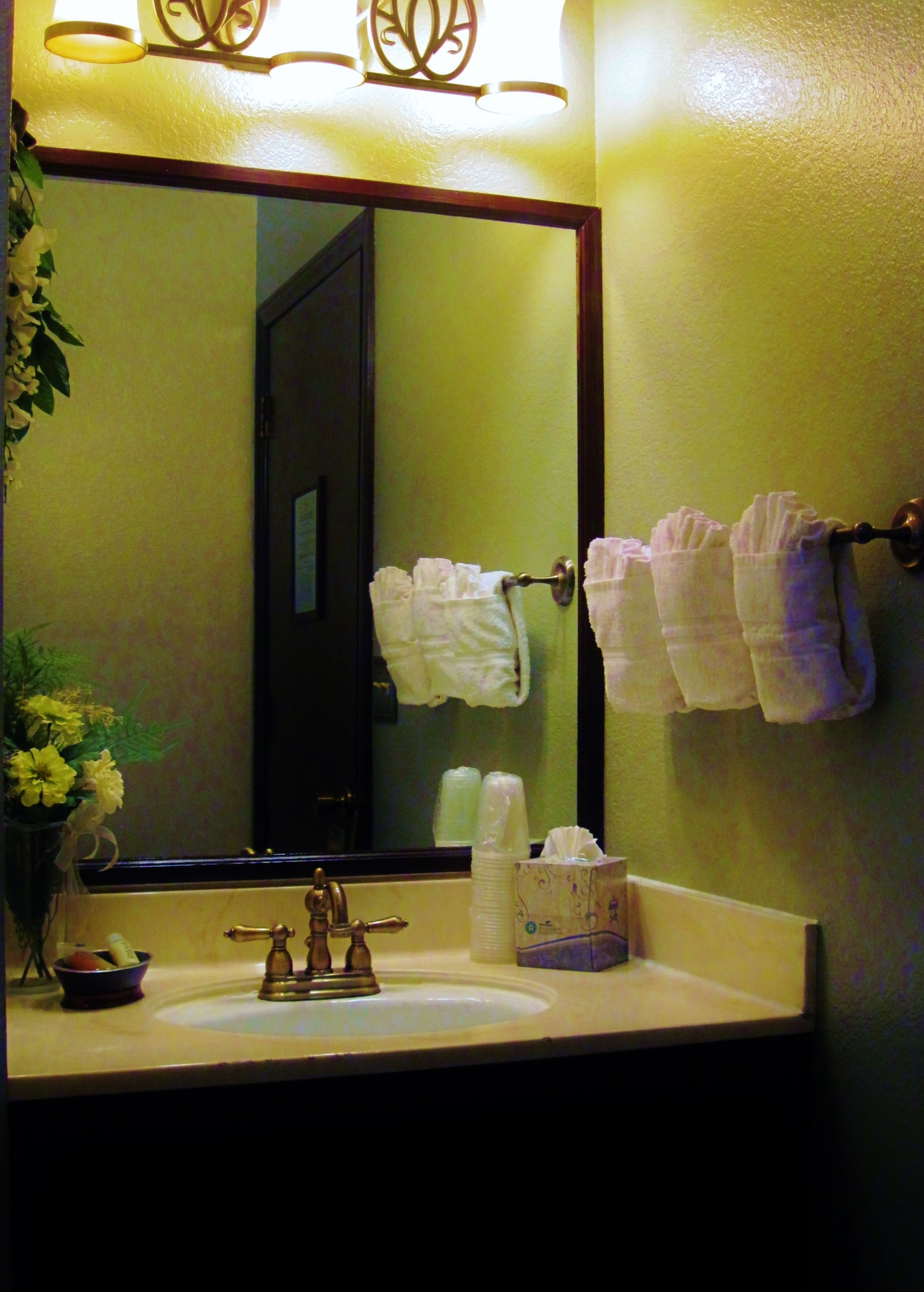 Un baño con lavamanos, espejo y perchero para toallas.