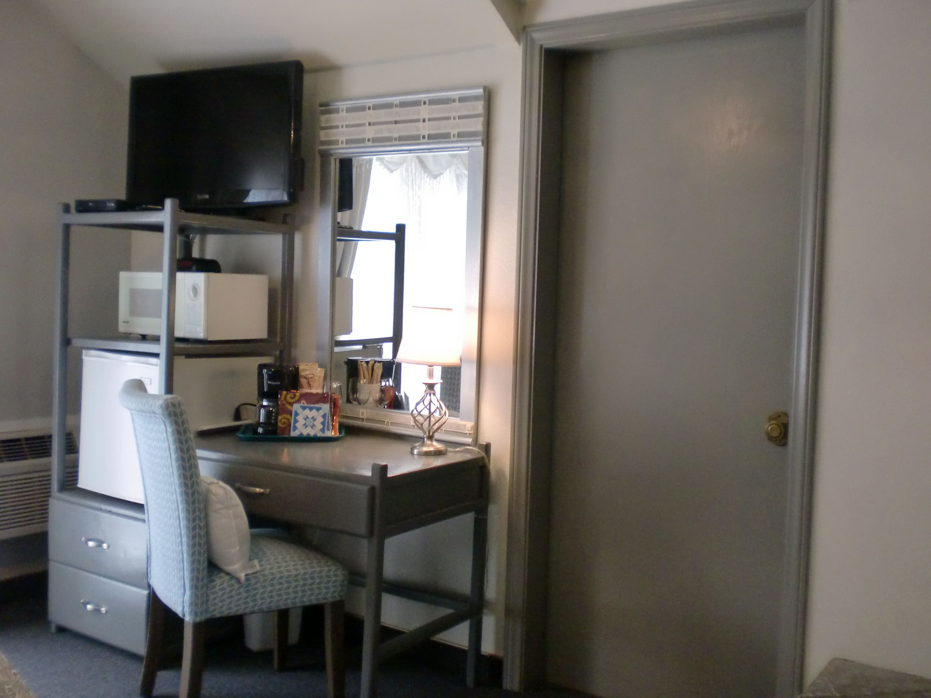 A compact bedroom with a desk, chair, and a television mounted above the desk.