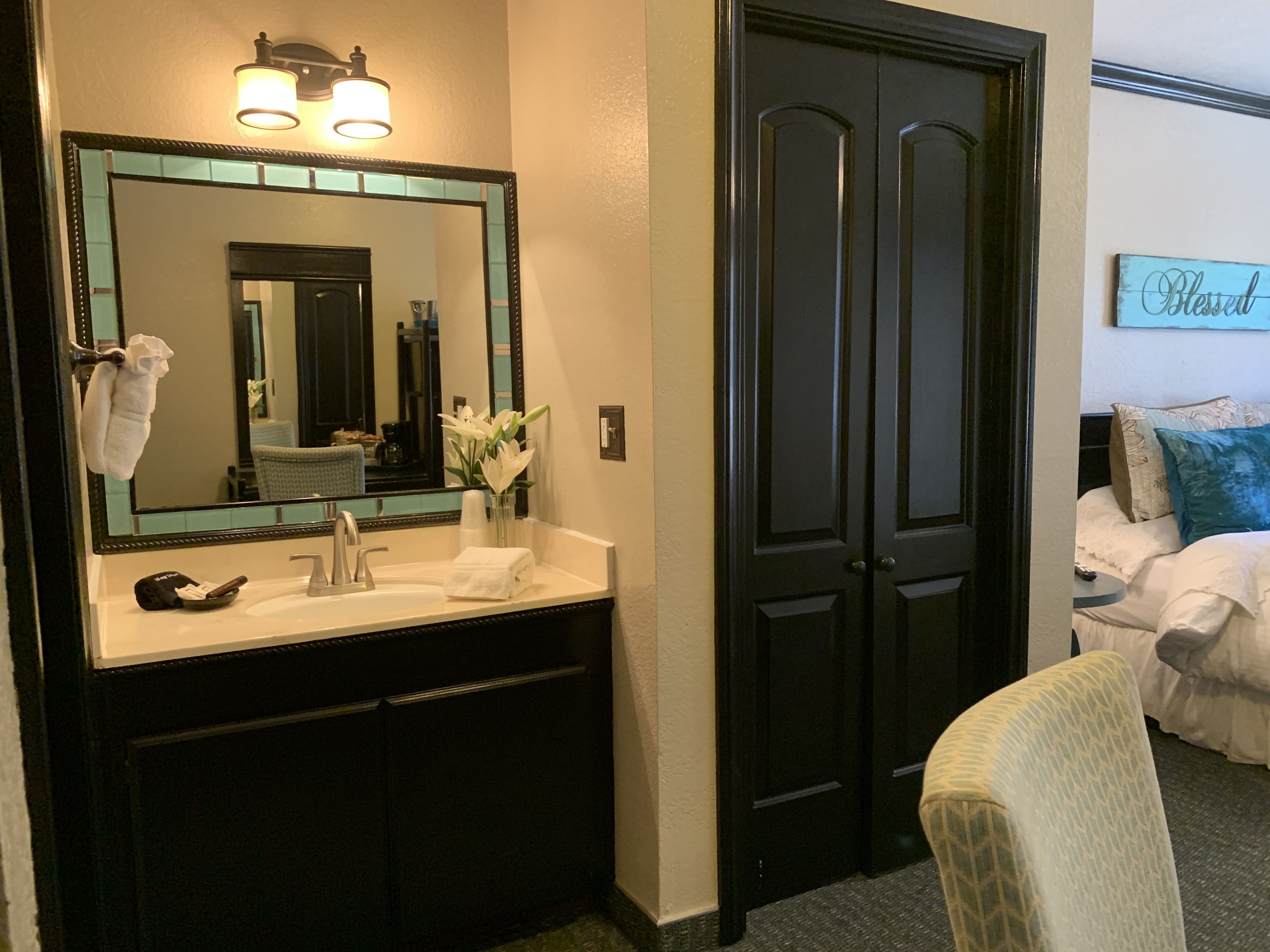A hotel bathroom with a large mirror, a sink, and a towel rack.