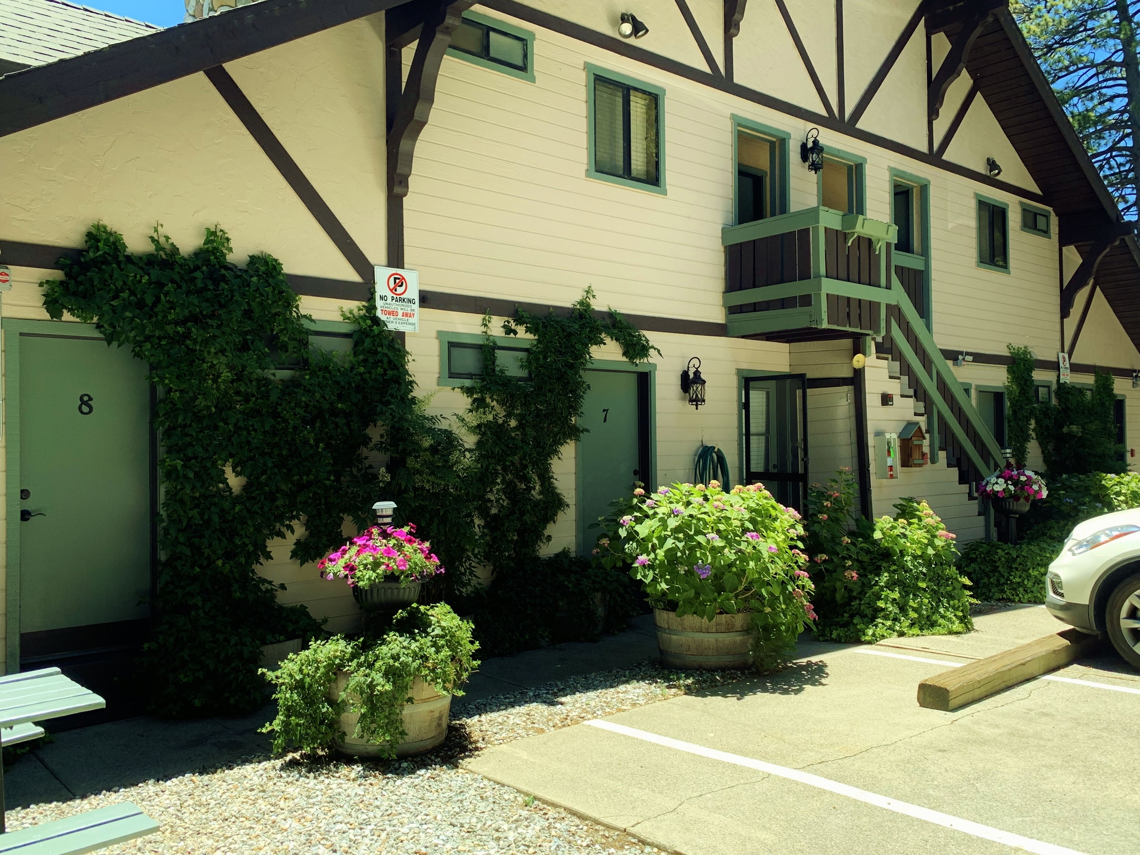 A two-story building with a 'No Parking' sign, a green door labeled '8', and a staircase leading to the upper floor.