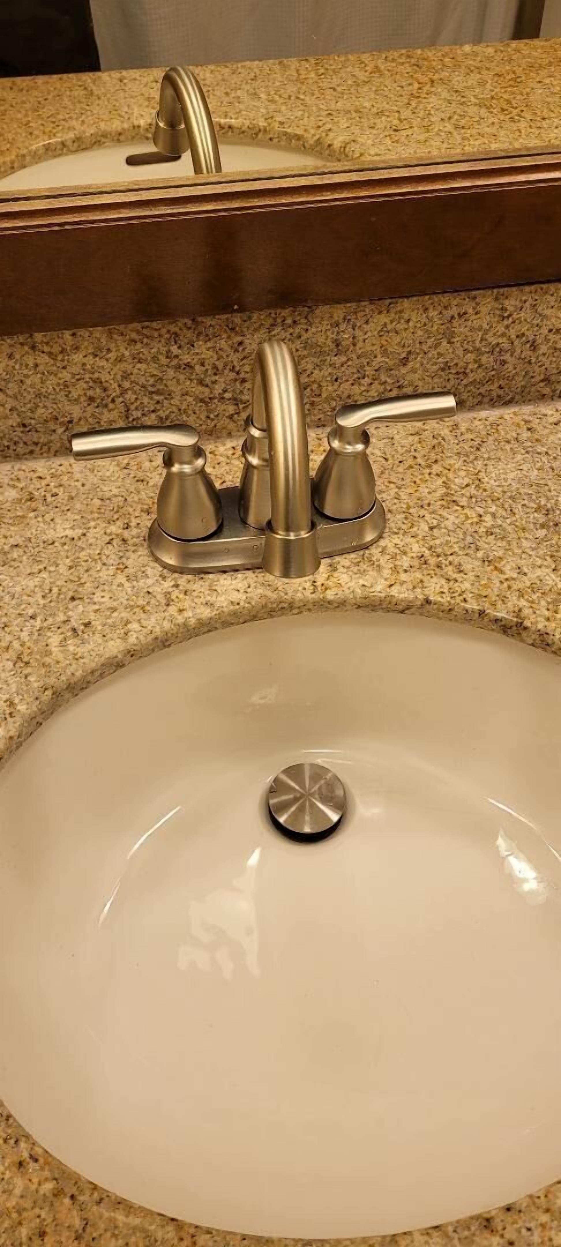 Un lavabo de salle de bain avec un seul robinet et un miroir au-dessus.