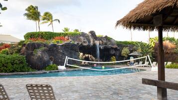 Relax by the pool surrounded by lush greenery and a natural rock formation.
