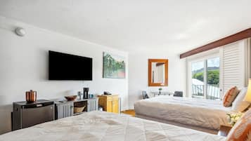 A hotel room with two beds, a TV, a painting, a window with blinds, and a small table with a chair.
