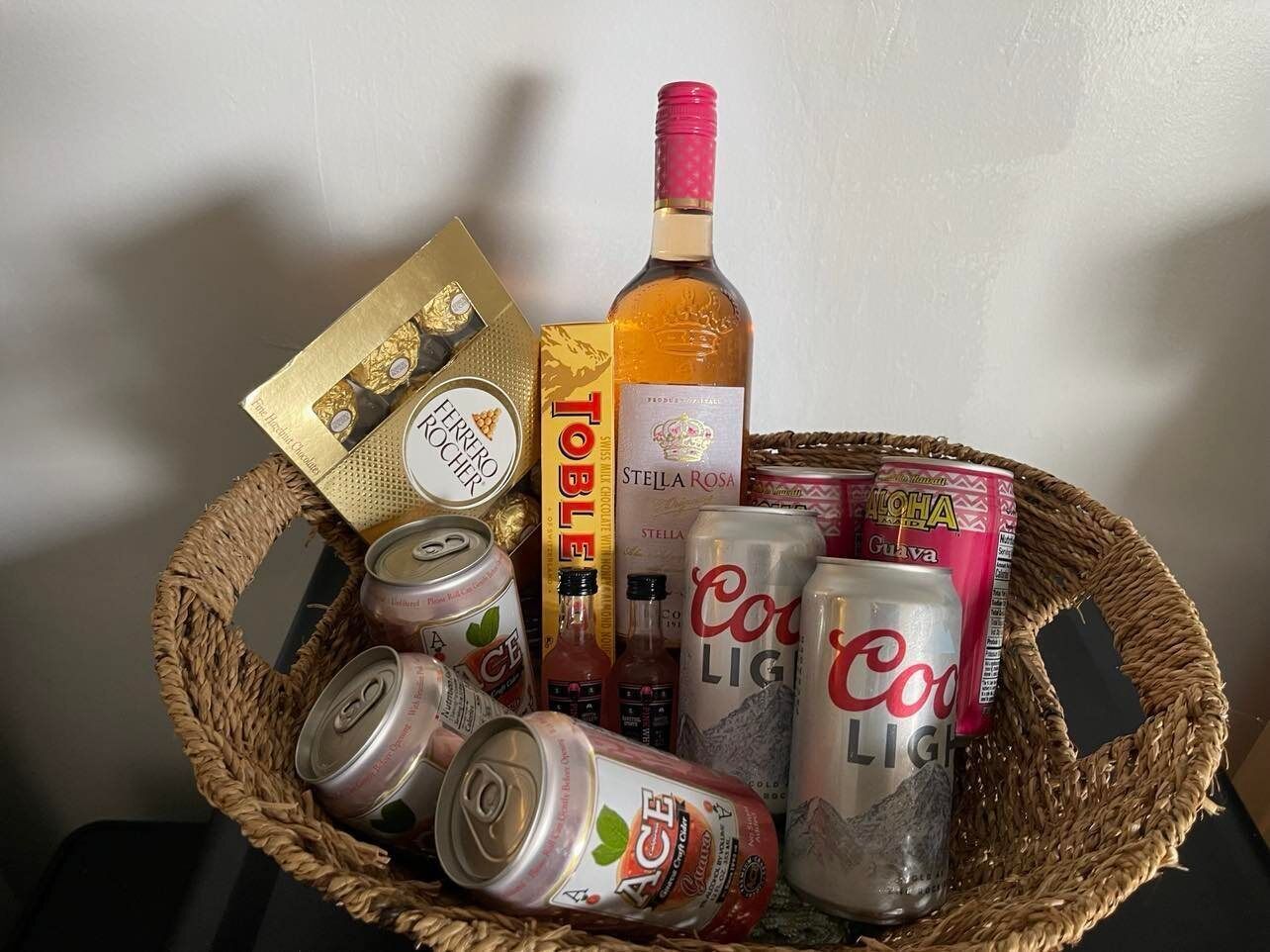 Una cistella amb diverses begudes, incloent llaunes de Coca-Cola Light, una ampolla de Stella Rosa i una llauna de guayaba.