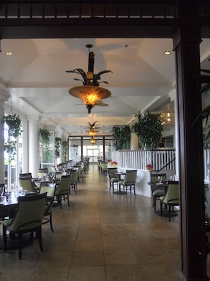 A spacious indoor dining area with multiple tables and chairs, a high ceiling with decorative lighting, and large windows allowing natural light. - 2417 at Lihue Oceanfront Resort (Lihue)