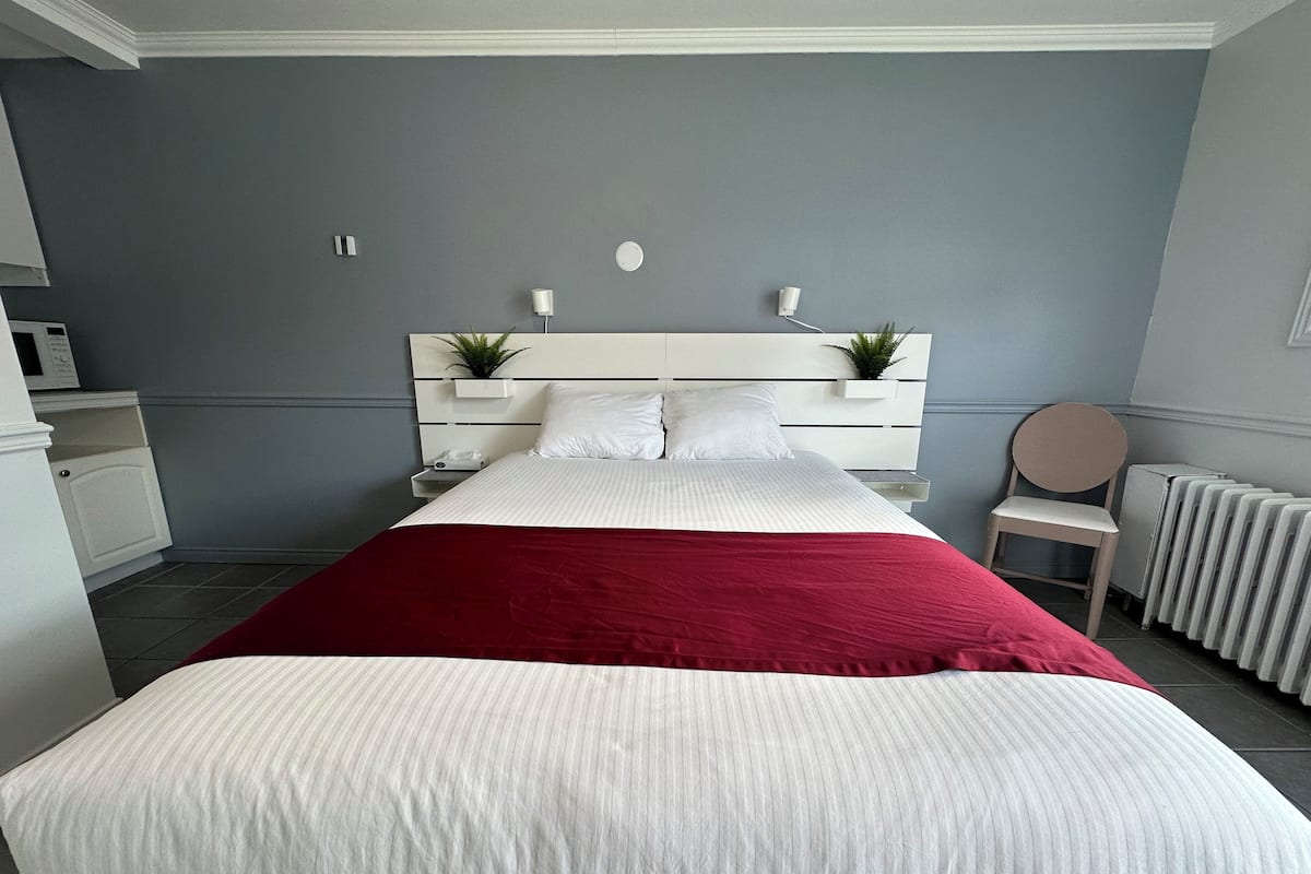 A neatly arranged bedroom with a bed, bedside tables, a chair, and a radiator.