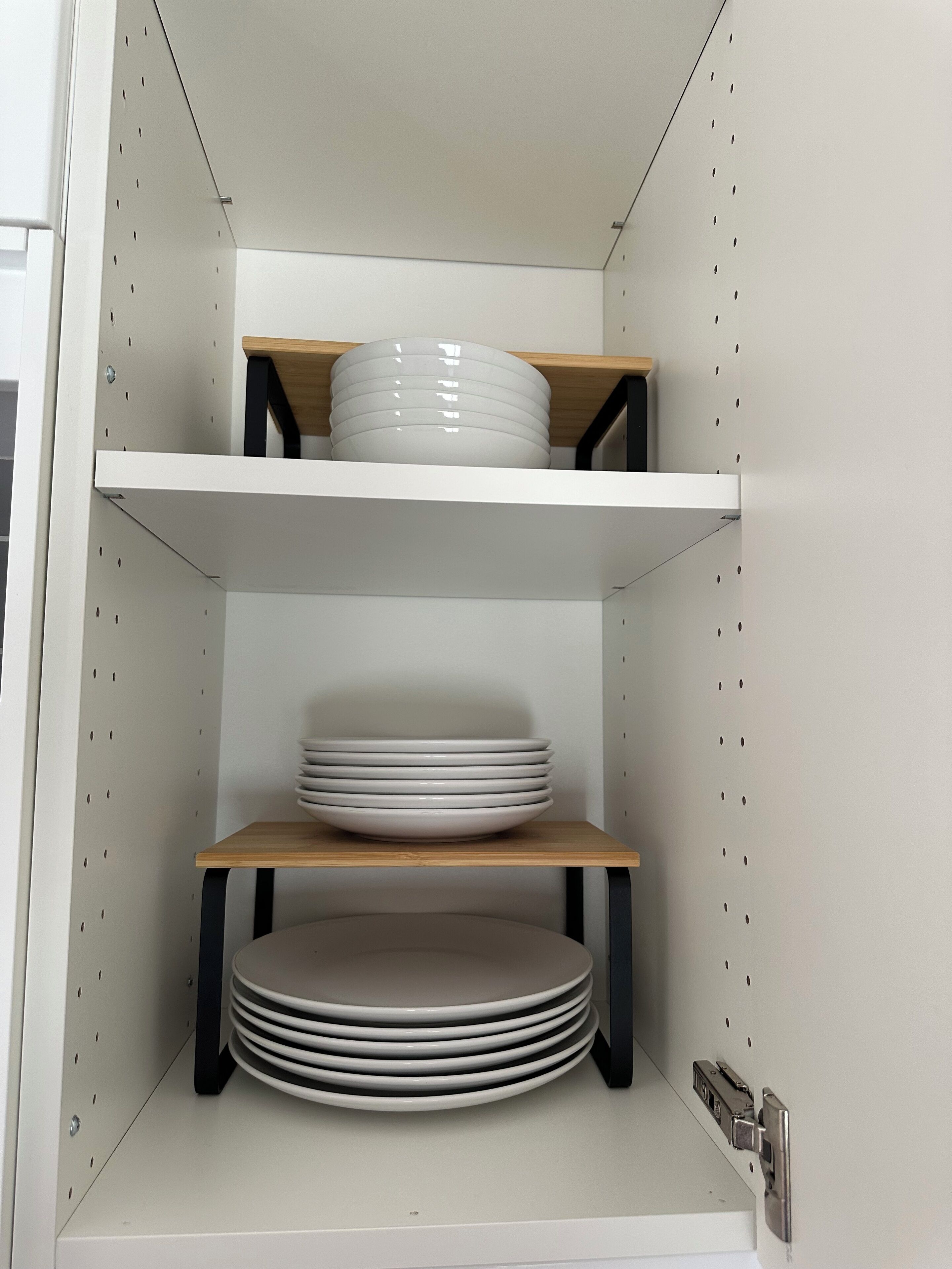 A kitchen cabinet with two shelves, each holding plates.