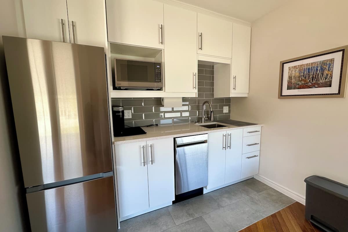 A modern kitchen with white cabinets, stainless steel appliances, and a tiled backsplash.