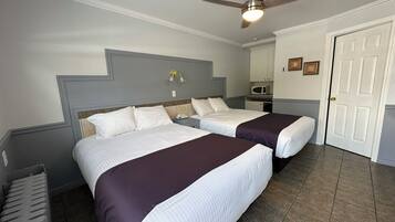Une chambre d’hôtel avec deux lits, un ventilateur de plafond, un four à micro-ondes et une porte.