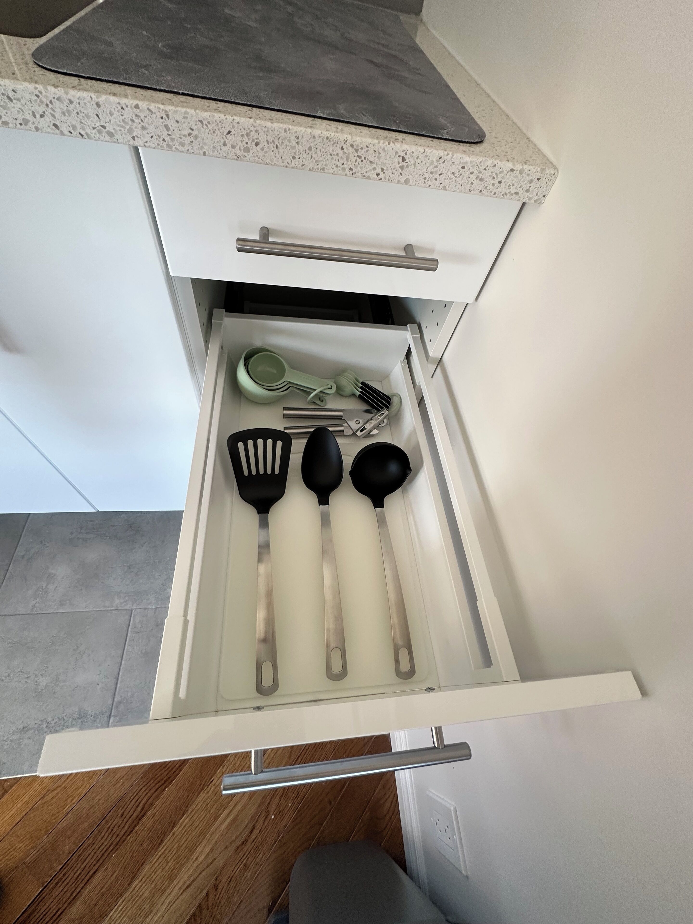 A kitchen drawer with utensils including spatulas, a ladle, and a grater.