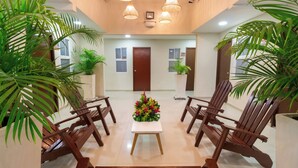 A hotel lobby with a reception desk, wooden chairs, potted plants, and a floral centerpiece. - Hotel Azuan Suites By Geh Suites (Cartagena)