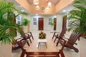 A hotel lobby with a reception desk, wooden chairs, potted plants, and a floral centerpiece. - Hotel Azuan Suites By Geh Suites (Cartagena)