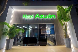 L’entrée de l’hôtel Azuan présente un design moderne, avec une façade en verre et une enseigne lumineuse.