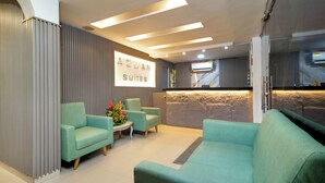 A hotel reception area with a modern design, featuring a reception desk, seating area with sofas, and a wall-mounted sign. - Hotel Azuan Suites By Geh Suites (Cartagena)