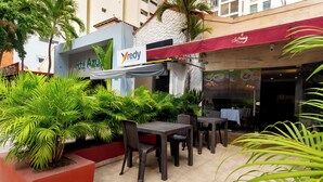 An outdoor seating area with tables and chairs, surrounded by lush green plants. - Hotel Azuan Suites By Geh Suites (Cartagena)