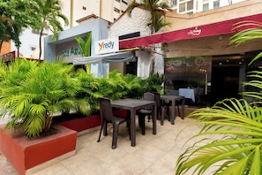 An outdoor seating area with tables and chairs, surrounded by lush green plants. - Hotel Azuan Suites By Geh Suites (Cartagena)