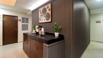Uma receção com design moderno, uma obra de arte emoldurada acima e uma planta em vaso no balcão.