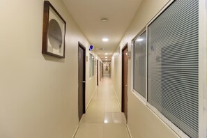 Un couloir avec des portes, un tableau encadré et un panneau sur le mur.
