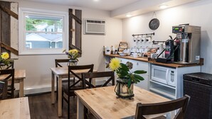 A modern kitchen with wooden tables and chairs, a coffee machine, and a microwave.