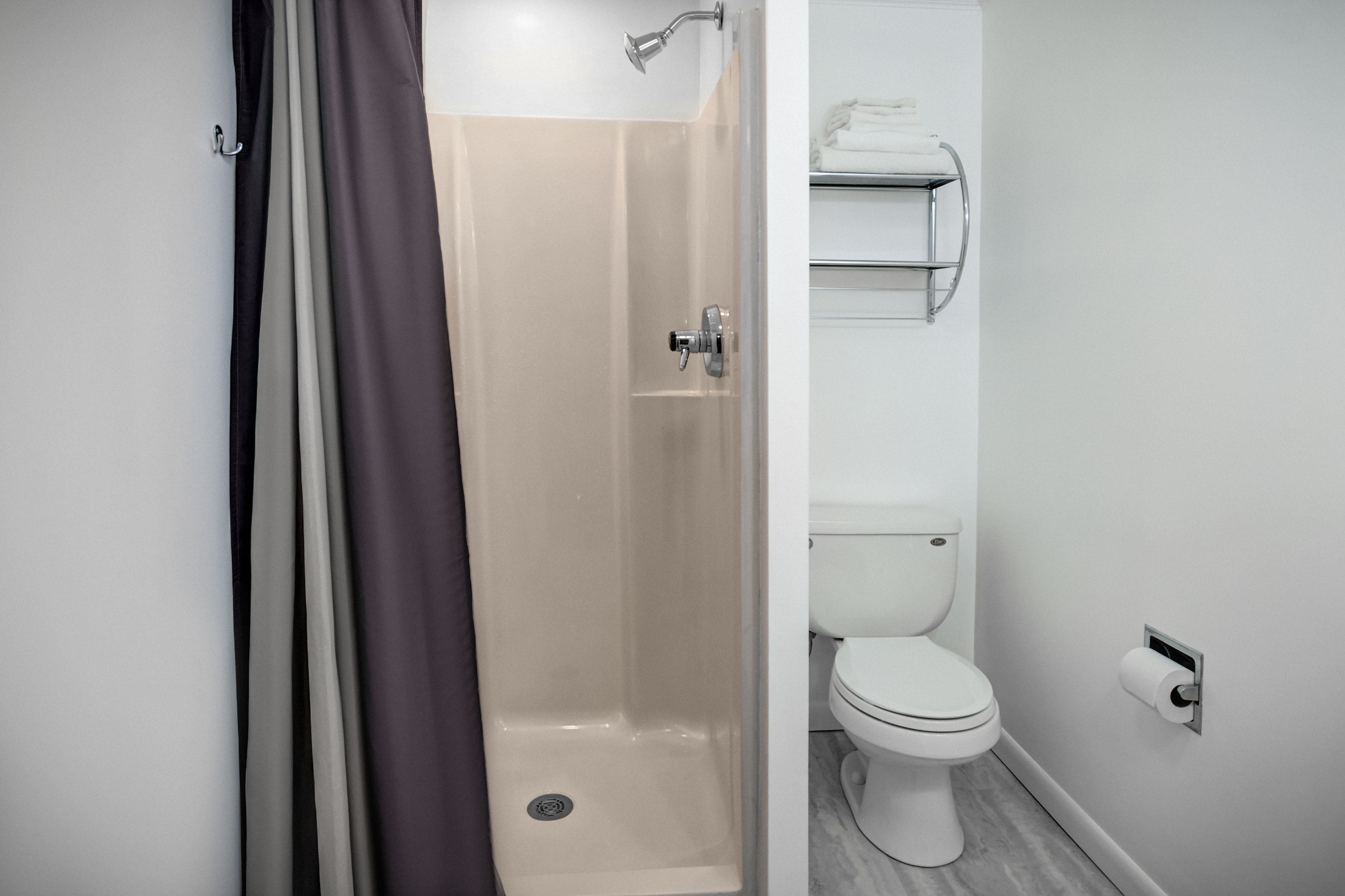 Ein modernes Badezimmer mit Dusche, Toilette und Handtuchhalter.