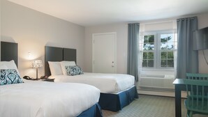 A hotel room with two beds, a desk, a chair, a TV, a window with curtains, and a door.