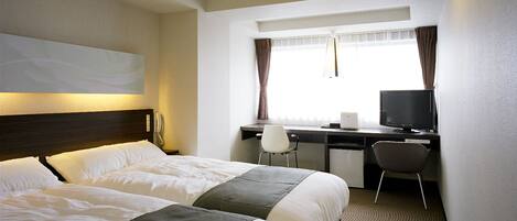 A hotel room with a bed, a desk, a chair, a television, and a small refrigerator.